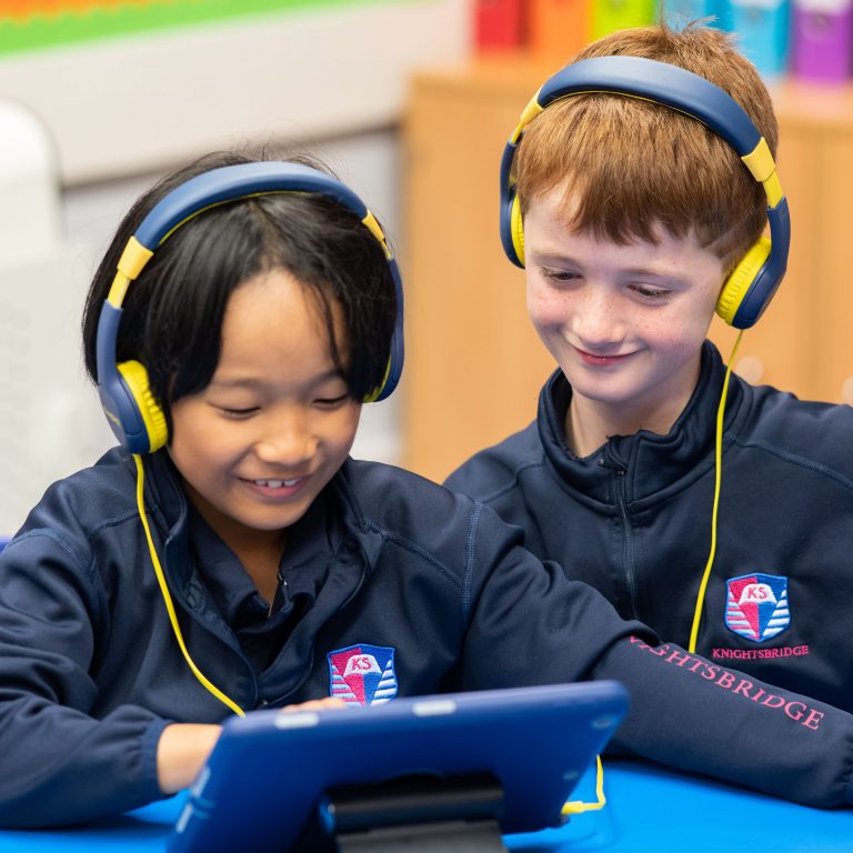 2 boys wearing headphones as they interact with an iPad
