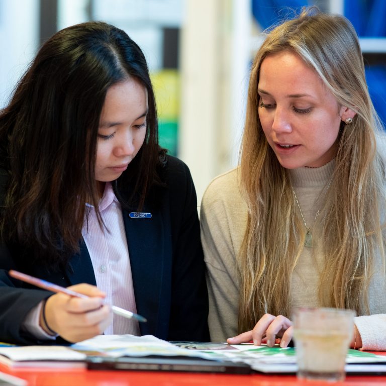 A student and a teacher looking at their assignments at their desk