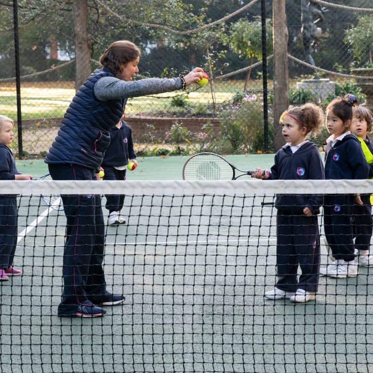 A teacher directs a child about how to play tennis