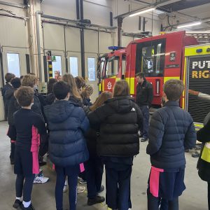 A group of students at the fire station, with a fire engine in the background
