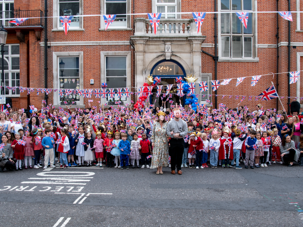 Reception pupils standing outside Knightsbridge School in London celebrating the coronation.