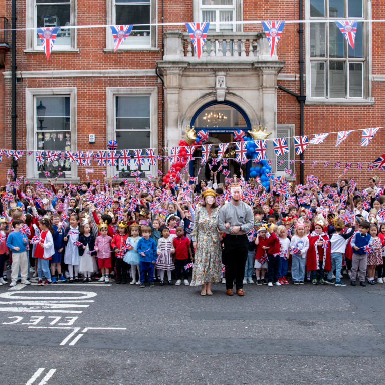 Reception pupils standing outside Knightsbridge School in London celebrating the coronation.